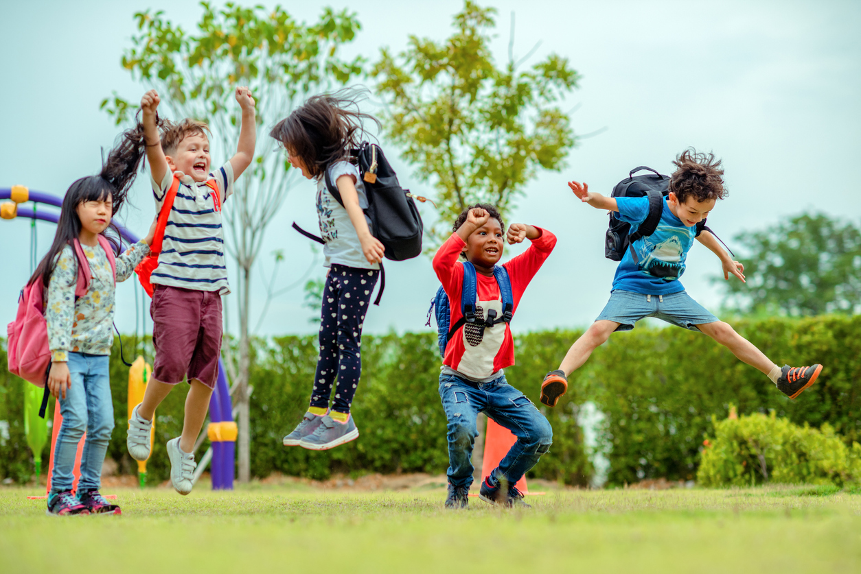 kids playing and jumping in a field after school