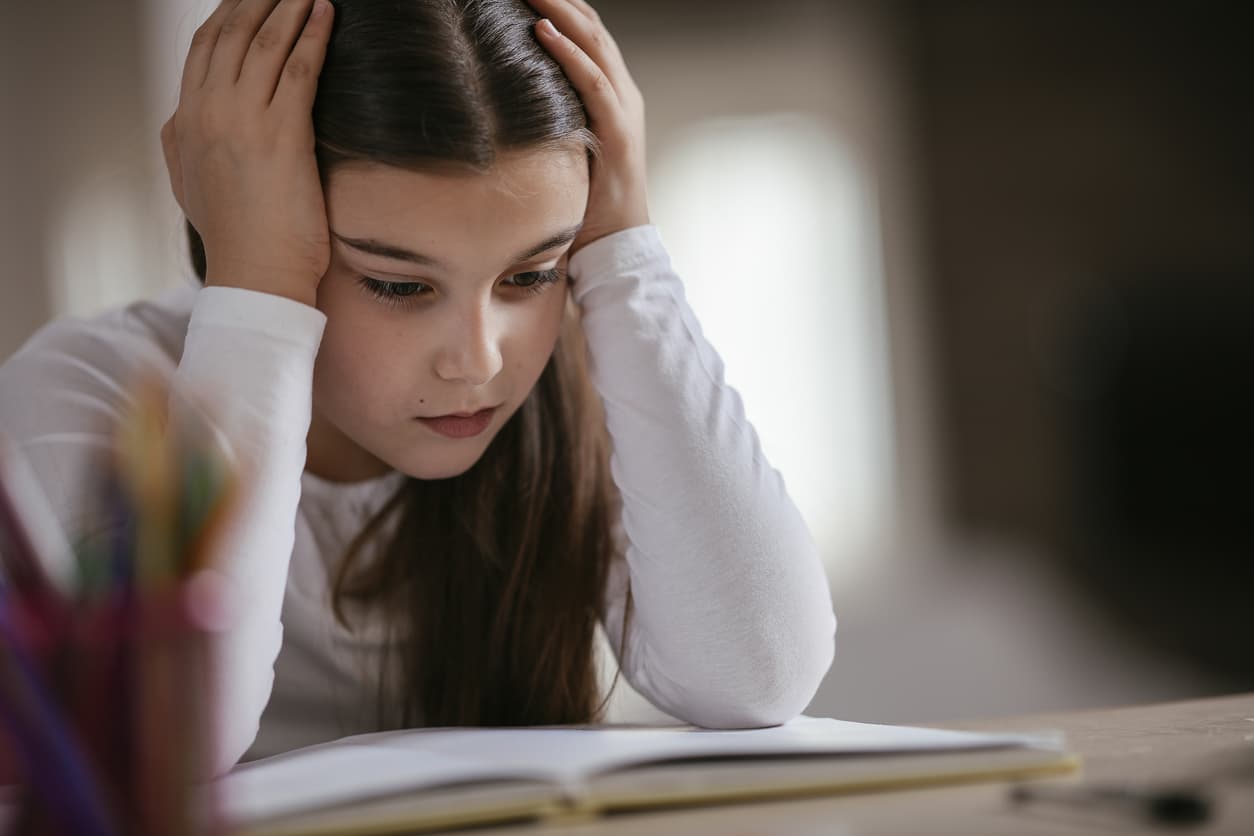 A young girl struggling to read a book after being subjected to the wait-and-see approach to learning