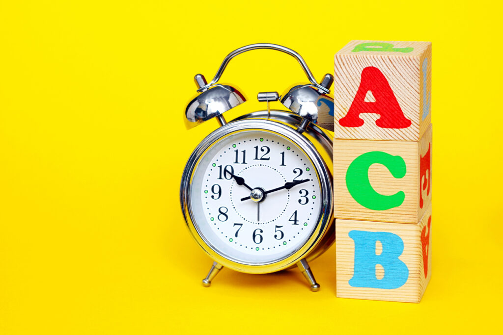 Alarm clock next to stacked blocks spelling ACB signifies dyslexia