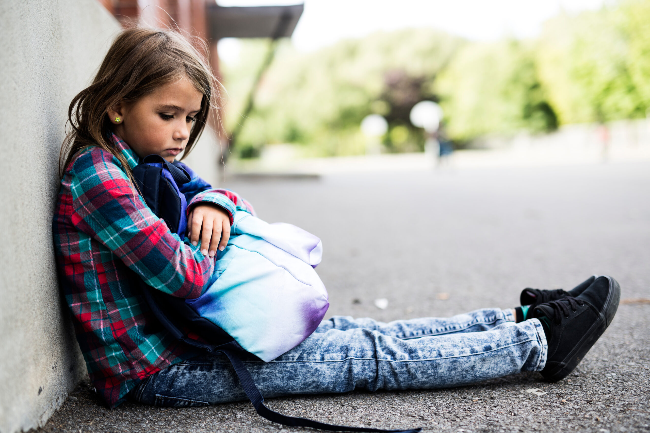sad girl sitting on the ground with backpack