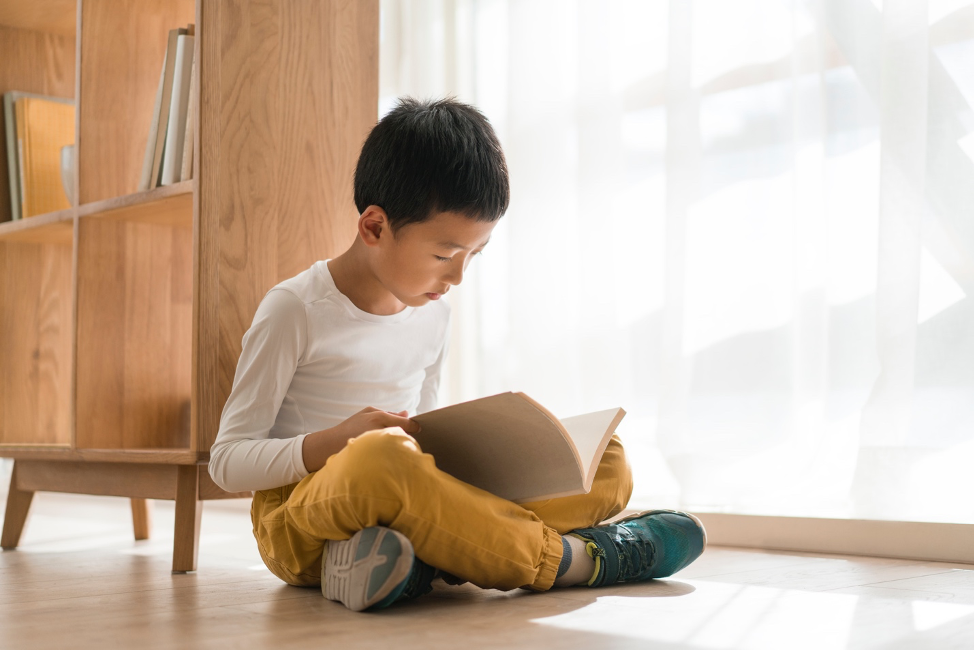 boy reading a book sitting on the floor