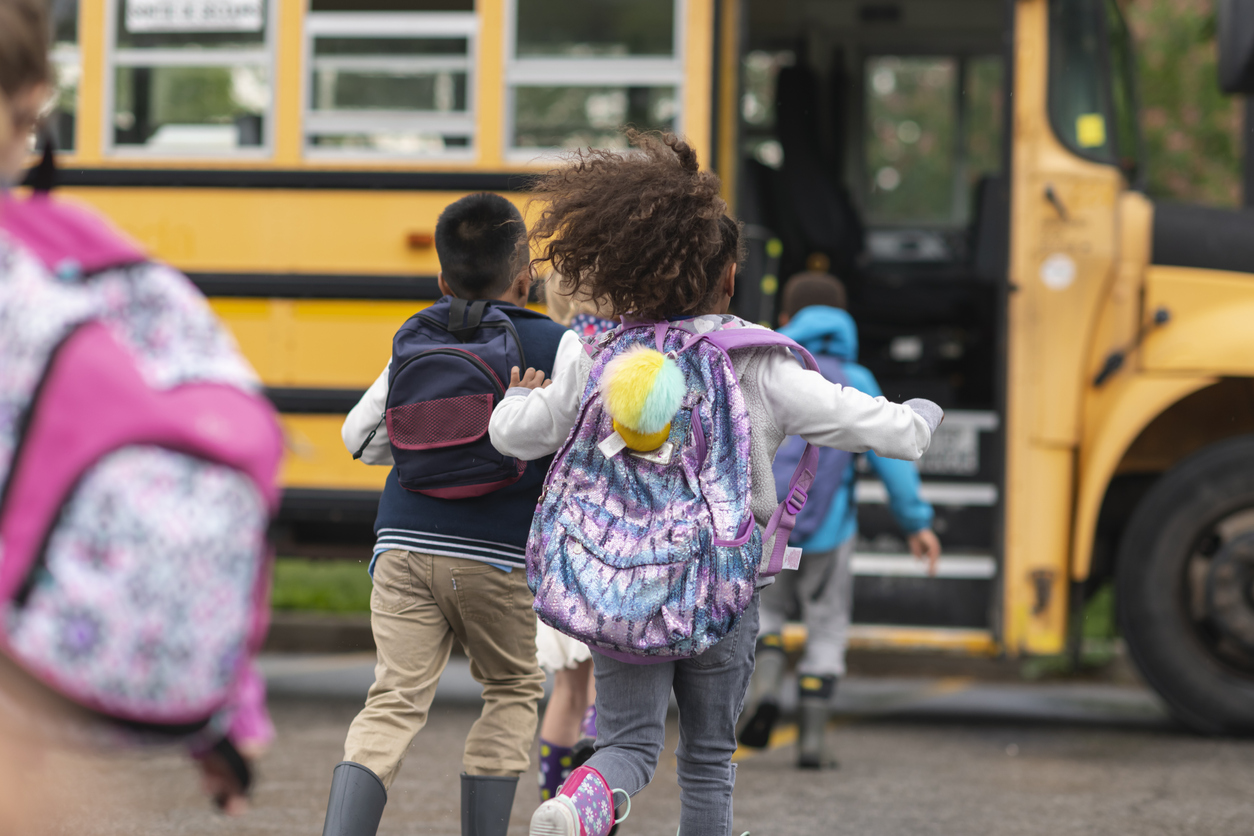 Children running to a school bus going back to school